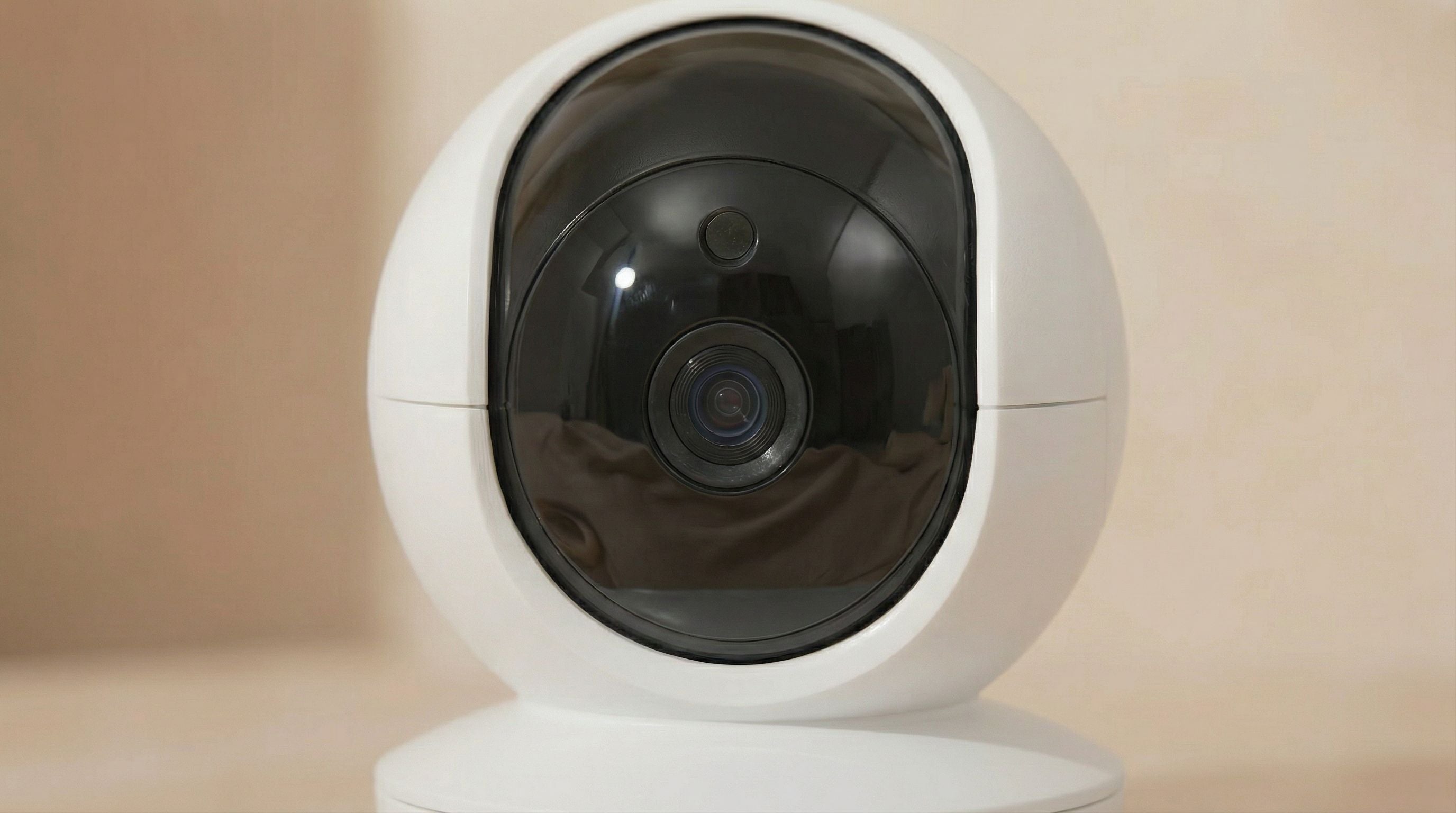 White security camera with black lens on a beige background