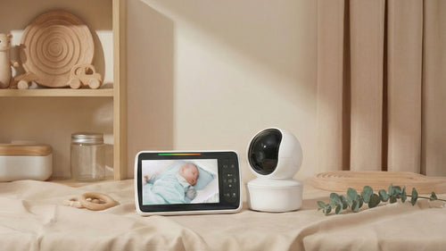 Baby monitor with screen displaying a baby and camera on a bed in a bedroom setting.